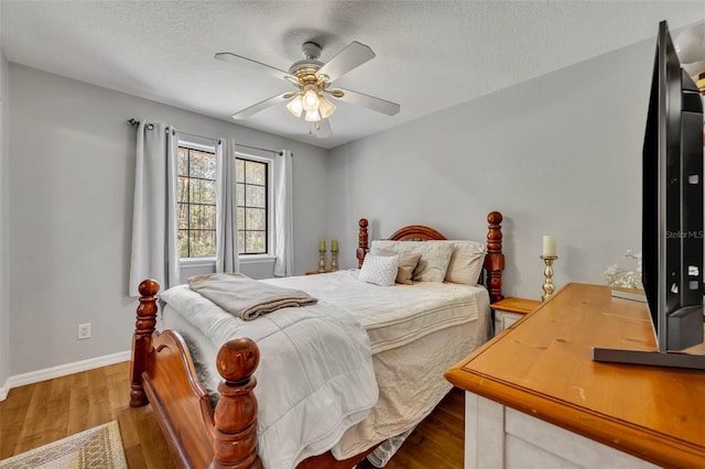 bedroom featuring ceiling fan, wood finished floors, baseboards, and a textured ceiling