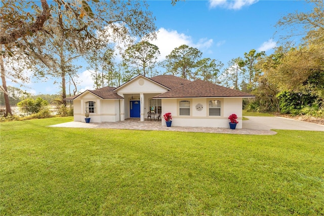 view of front of property with stucco siding, a front yard, and a shingled roof