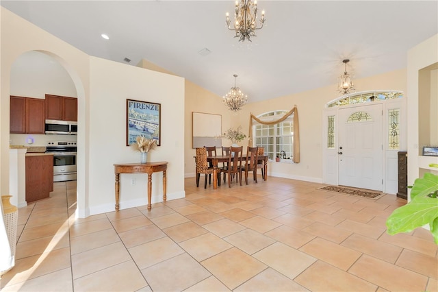 entrance foyer with light tile patterned floors, baseboards, high vaulted ceiling, and a chandelier