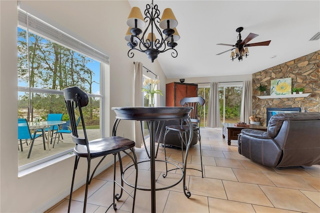 dining room featuring light tile patterned floors, a ceiling fan, visible vents, a fireplace, and vaulted ceiling