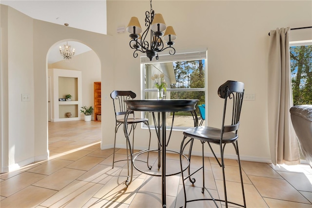 dining space with light tile patterned floors, a notable chandelier, and built in features