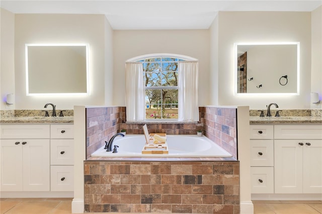 bathroom featuring a sink, two vanities, a bath, and tile patterned floors