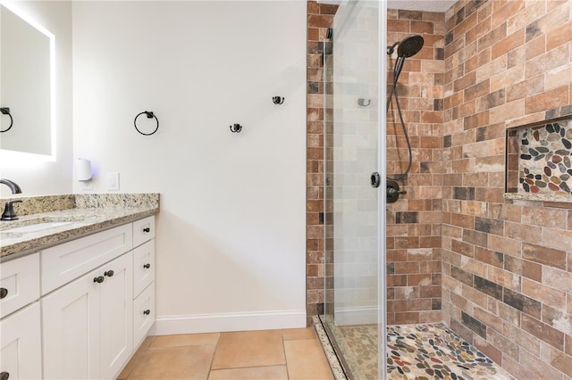 bathroom with baseboards, a stall shower, vanity, and tile patterned flooring