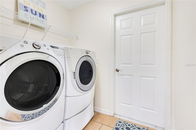 washroom featuring laundry area, light tile patterned floors, baseboards, and washer and clothes dryer