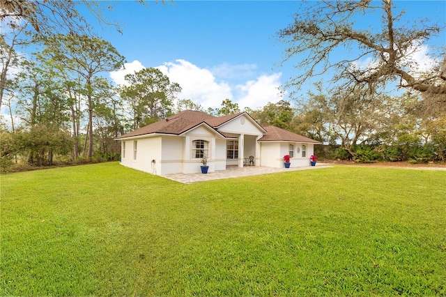 rear view of property featuring a patio area, stucco siding, and a yard