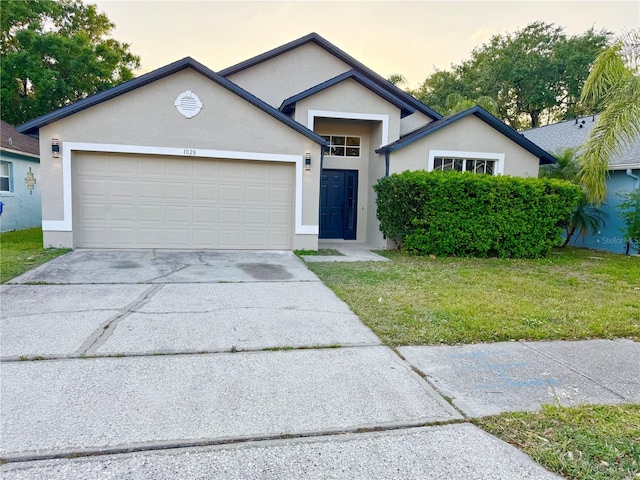 ranch-style house with stucco siding, an attached garage, driveway, and a yard