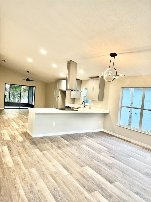 kitchen featuring open floor plan, light countertops, light wood-style floors, and island range hood