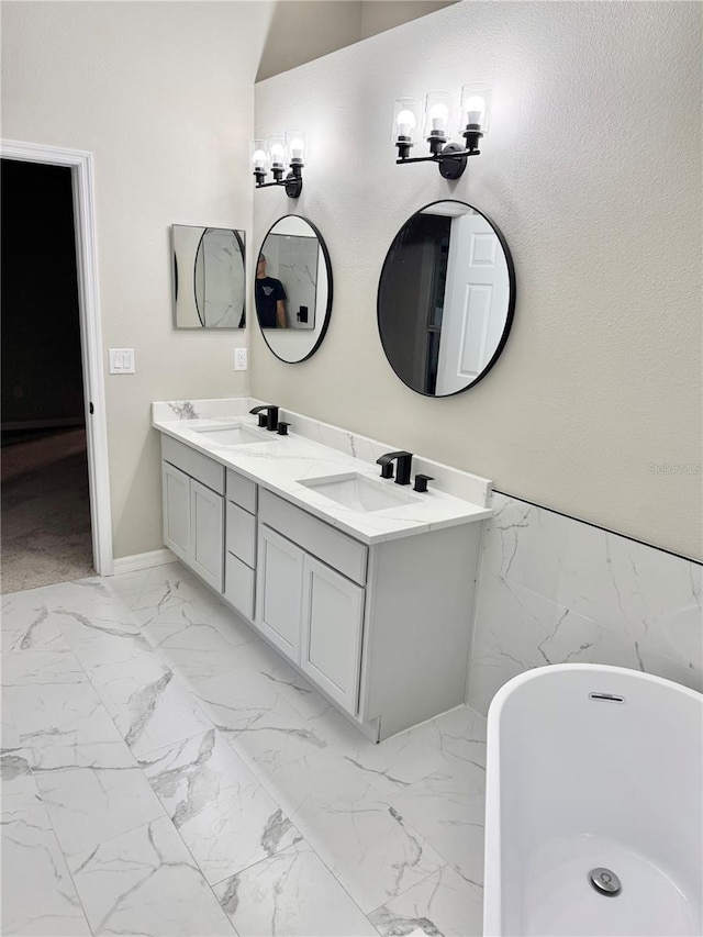 full bathroom featuring a soaking tub, double vanity, marble finish floor, and a sink