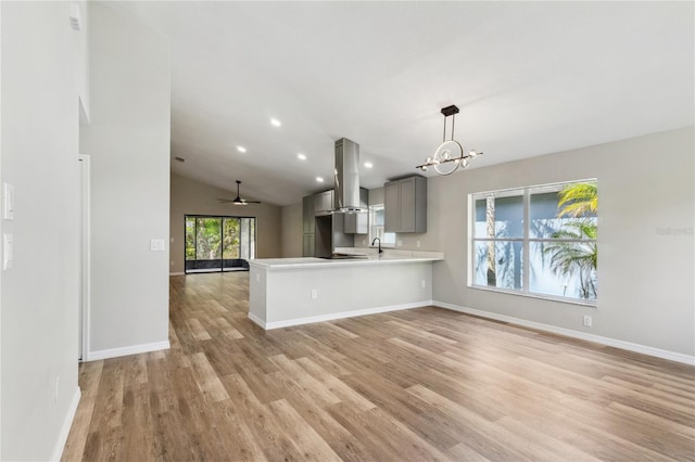 kitchen featuring open floor plan, island exhaust hood, gray cabinets, and light wood finished floors