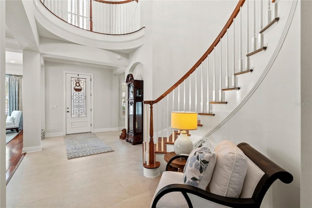 foyer entrance featuring arched walkways, baseboards, stairs, and a towering ceiling