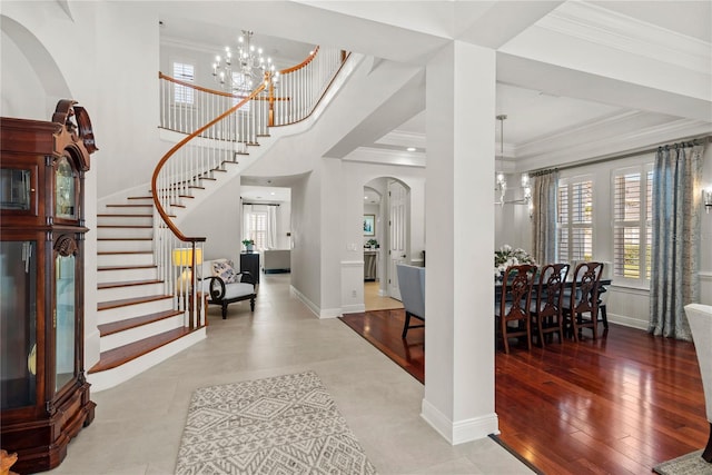 entryway featuring wood finished floors, stairway, an inviting chandelier, crown molding, and baseboards