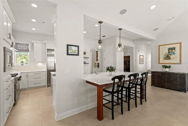 kitchen featuring a breakfast bar, white cabinetry, light countertops, decorative backsplash, and high end appliances