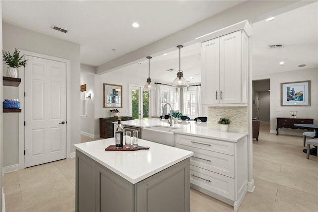 kitchen featuring visible vents, a sink, decorative backsplash, light countertops, and white cabinets