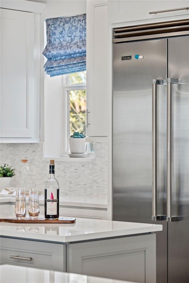 bar featuring decorative backsplash and stainless steel built in fridge