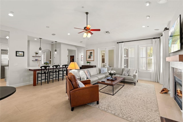 living area with visible vents, baseboards, ceiling fan, a tiled fireplace, and recessed lighting