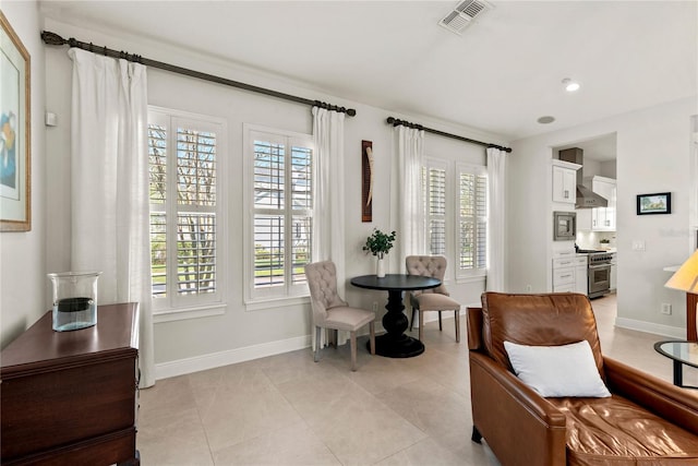 living area with light tile patterned flooring, visible vents, plenty of natural light, and baseboards