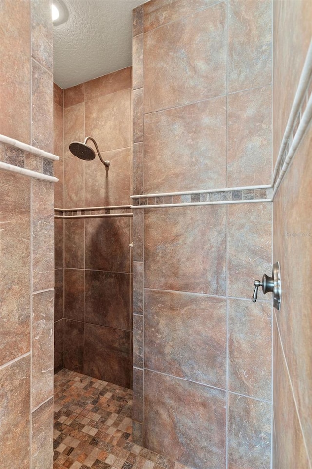 full bathroom featuring a tile shower and a textured ceiling