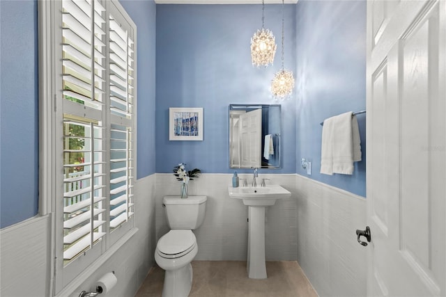 half bath featuring toilet, tile walls, wainscoting, and tile patterned flooring