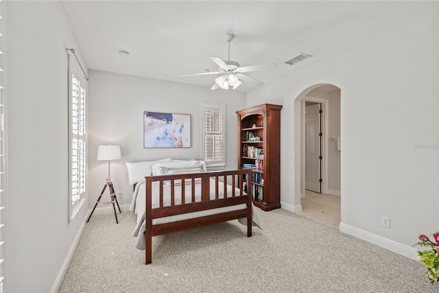 bedroom with arched walkways, visible vents, light colored carpet, and multiple windows