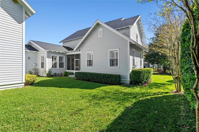 rear view of house featuring a lawn and a sunroom