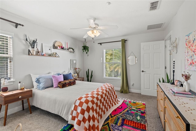 bedroom with visible vents, light colored carpet, baseboards, and ceiling fan