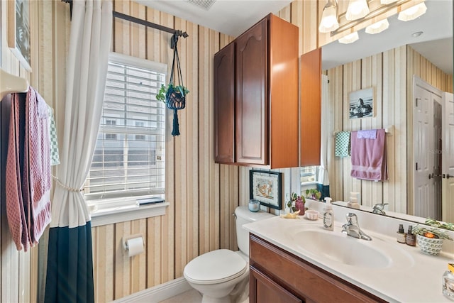 half bath featuring visible vents, wallpapered walls, baseboards, toilet, and vanity