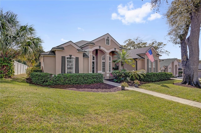 mediterranean / spanish-style home featuring stucco siding, a front lawn, and fence