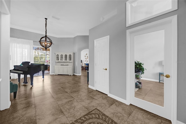 corridor featuring visible vents, a notable chandelier, arched walkways, crown molding, and baseboards