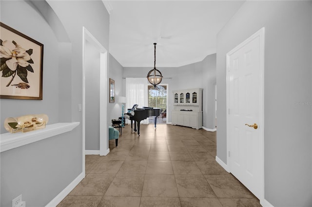 corridor with baseboards, an inviting chandelier, and tile patterned flooring