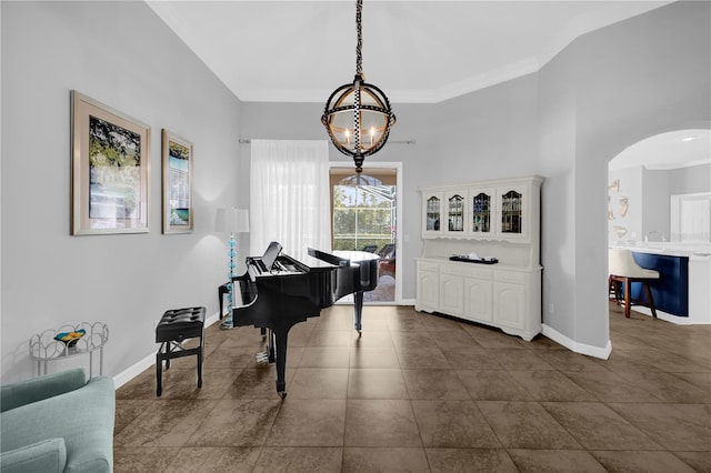 sitting room featuring baseboards, arched walkways, an inviting chandelier, and crown molding