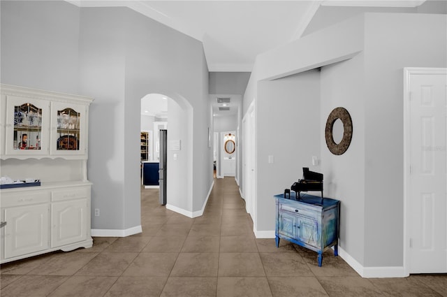 hall with arched walkways, light tile patterned floors, and baseboards