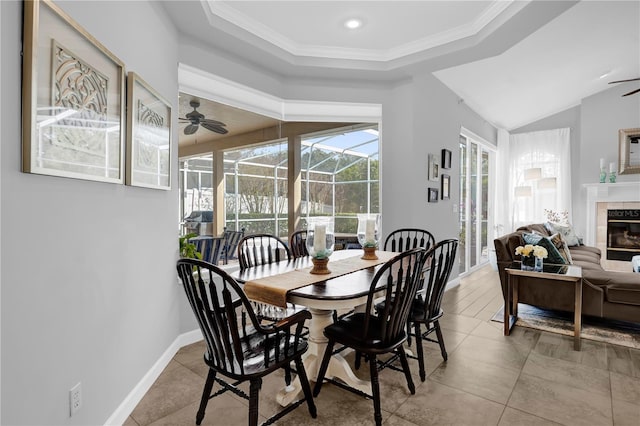 dining space featuring baseboards, ceiling fan, a tiled fireplace, ornamental molding, and a sunroom