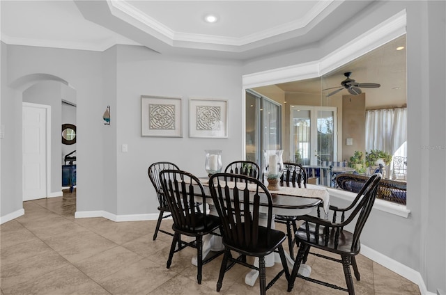 dining area featuring ceiling fan, baseboards, arched walkways, and ornamental molding