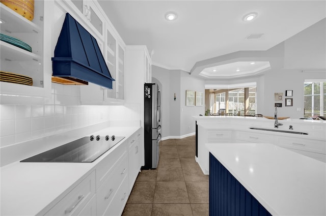 kitchen with premium range hood, a sink, tasteful backsplash, freestanding refrigerator, and black electric stovetop