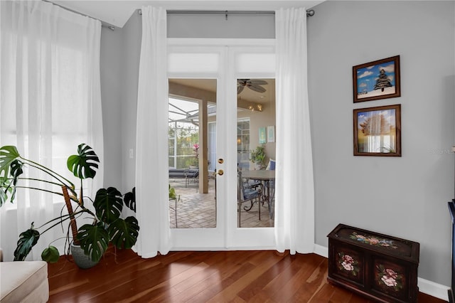 doorway to outside with baseboards, a ceiling fan, and dark wood-style flooring