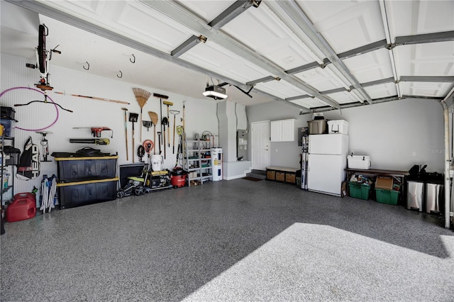 garage featuring water heater, a garage door opener, and freestanding refrigerator