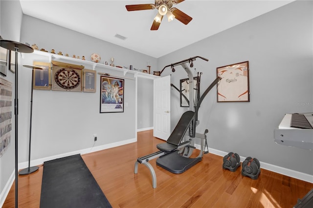 exercise area with wood finished floors, a ceiling fan, visible vents, and baseboards