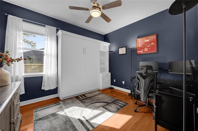 office area featuring baseboards, wood finished floors, and a ceiling fan