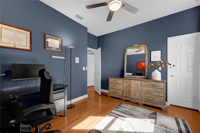 home office with a ceiling fan, visible vents, light wood finished floors, and baseboards