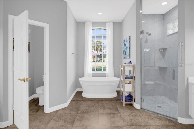 bathroom featuring a freestanding tub, toilet, baseboards, and a stall shower