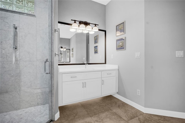 bathroom featuring a tile shower, vanity, and baseboards