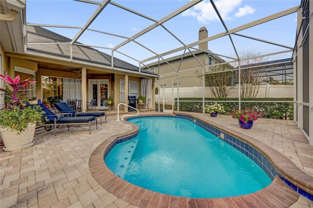 view of swimming pool with a fenced in pool, ceiling fan, fence, glass enclosure, and a patio