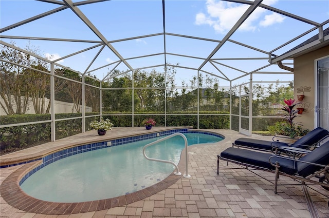 outdoor pool featuring glass enclosure and a patio