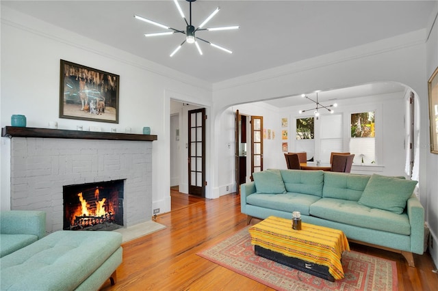 living room with a chandelier, arched walkways, wood finished floors, and ornamental molding