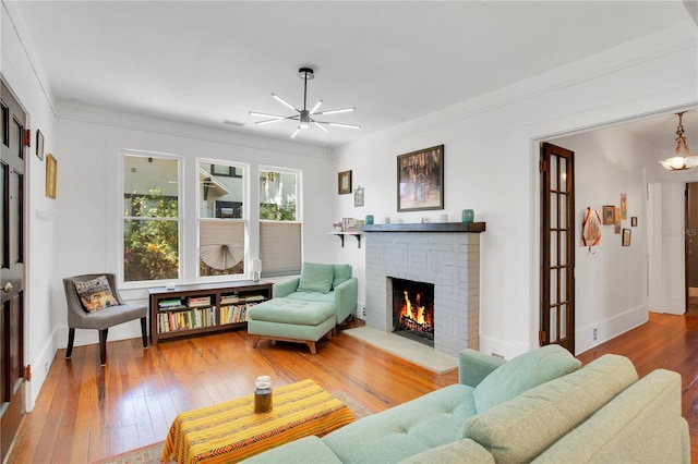 living room featuring baseboards, a brick fireplace, ceiling fan, and hardwood / wood-style flooring