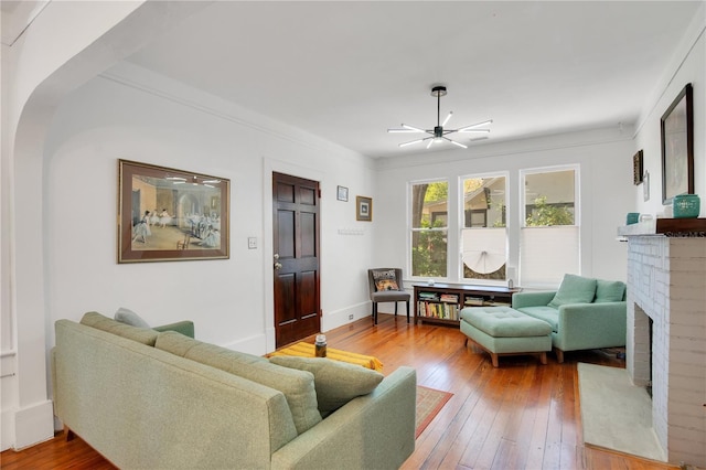 living room featuring crown molding, baseboards, a fireplace, a ceiling fan, and wood-type flooring