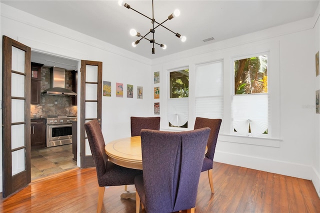 dining space featuring visible vents, an inviting chandelier, and wood finished floors