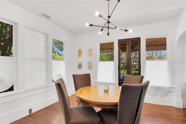 dining space featuring a chandelier, visible vents, a healthy amount of sunlight, and wood finished floors