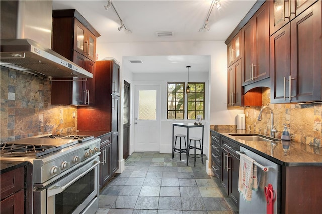 kitchen featuring backsplash, glass insert cabinets, appliances with stainless steel finishes, wall chimney exhaust hood, and a sink