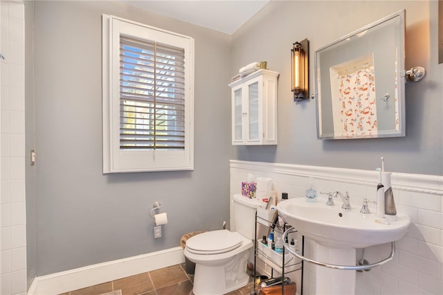 bathroom featuring tile patterned floors, a wainscoted wall, toilet, and baseboards